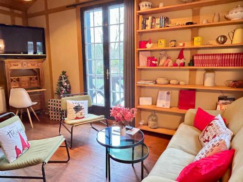 een woonkamer met een bank, stoelen en een tafel bij Le chalet bucolique au bord de l'eau in Olivet