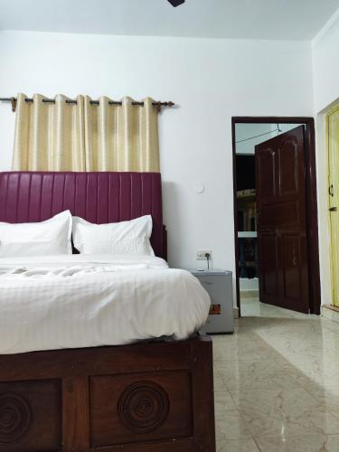 a bedroom with a bed with a purple headboard and a mirror at Quiet Coastal Hideaway Studio near Candolim Beach in Candolim