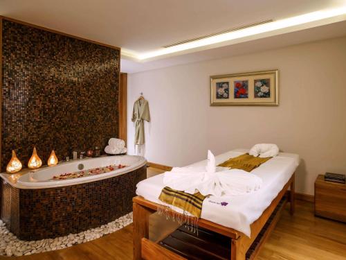a bathroom with a bath tub and a bed at Novotel Yangon Max in Yangon