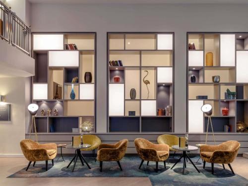 un vestíbulo con mesas, sillas y ventanas en Mercure Hotel Dortmund Centrum, en Dortmund