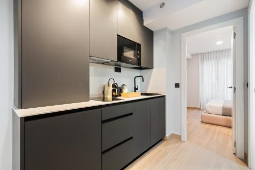 a kitchen with black cabinets and a bed in the background at Dobo Madrid Portugal in Madrid