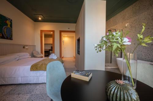 een slaapkamer met een bed en een tafel met een vaas met bloemen bij Des Bains Acireale in Acireale
