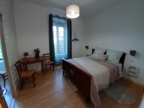 a bedroom with a bed and a table and a desk at Gîte À l'ombre du pommier in Ruynes-en-Margeride