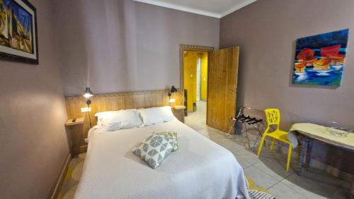 a bedroom with a bed and a table and a yellow chair at Le Clos Saint André in Banyuls-sur-Mer