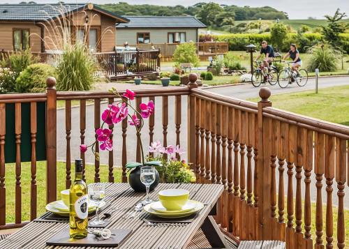 a wooden deck with a table with drinks and a man on a bike at Holderness Country Park in Tunstall
