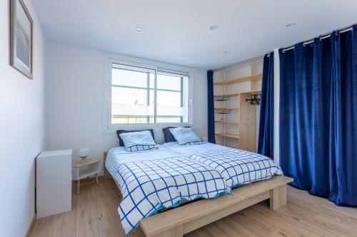 ein Schlafzimmer mit einem Bett und einem Fenster mit blauen Vorhängen in der Unterkunft Cocon Savinois - Vue Montagne in Savines