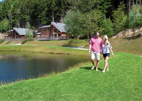 een man en een vrouw lopen over het gras bij een meer bij Penvale Lakes Lodges in Llangollen