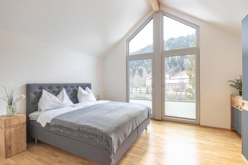 a bedroom with a large bed and large windows at Murleben Appartements - Nahe Red Bull Ring & Kreischberg in Stadl an der Mur