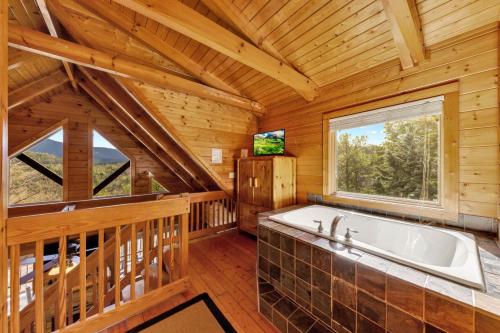a bathroom with a large tub in a cabin with a window at High Cotton Epic Views Hot Tub Pool Table in Sevierville