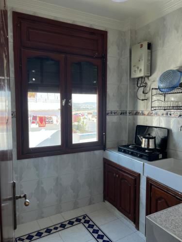 een keuken met een fornuis en een raam erin bij Blue Beach Apartments in Taghazout