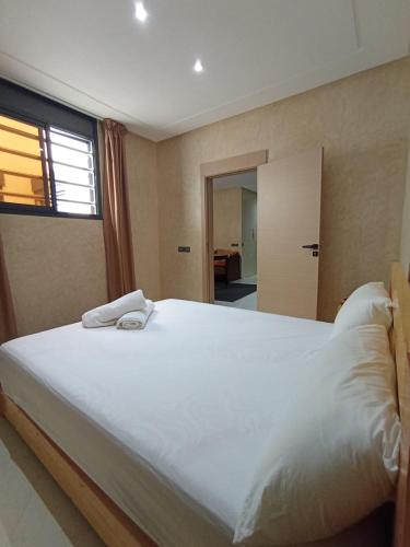 a bedroom with a large white bed with a window at Blue Wave Surf House in Mirleft