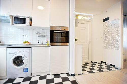 eine Küche mit einer Waschmaschine und einem karierten Boden in der Unterkunft Enjoy Apartman Eger in Eger