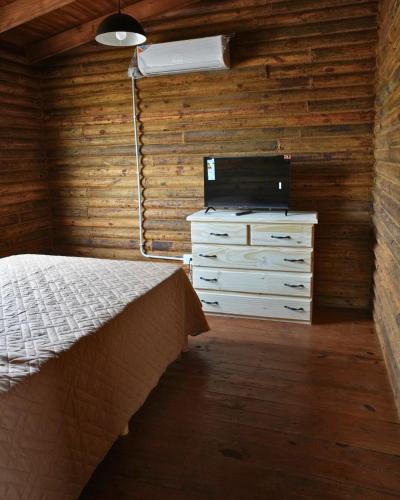 a bedroom with a bed and a dresser and a television at CABAÑAS BRUTUS RANCHs in Azul