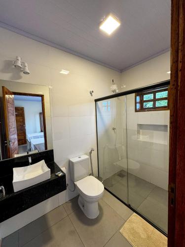 um banheiro com vaso sanitário e box de vidro em Hotel Uirapuru em Teresina de Goias