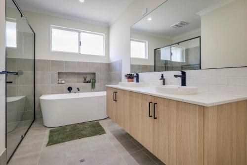a bathroom with a tub and two sinks and a bath tubermottermott at Isla Escape Pet Friendly Dunsborough in Dunsborough