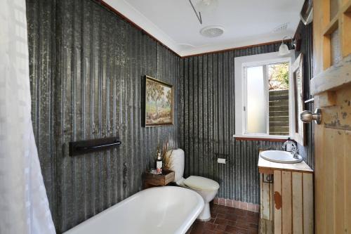 a bathroom with a tub and a toilet and a sink at Leura Haven Rustic Mountain Cottage in Leura