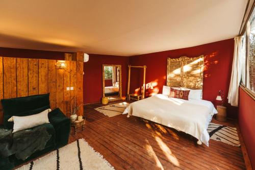 Oasis Garden Marrakech في مراكش: غرفة نوم بجدران حمراء وسرير واريكة