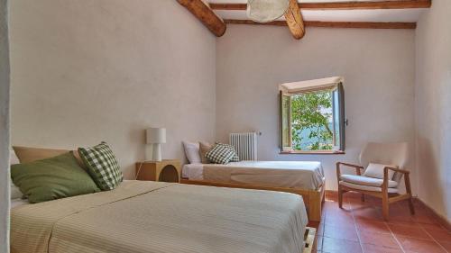 een kamer met 2 bedden, een stoel en een raam bij Tenuta Seriole 10 in Bibbiena