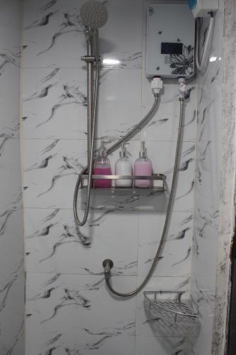 a bathroom with a shower with purple soap dispensers at Balay Degay Transient House in Baguio