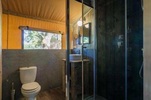 een badkamer met toilet en glazen douche bij Camping 5 étoiles - Piscine - ccbefbi in Gourdon-en-quercy