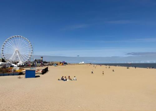 a group of people sitting on a beach with a ferris wheel at The Carlton Hotel in Great Yarmouth