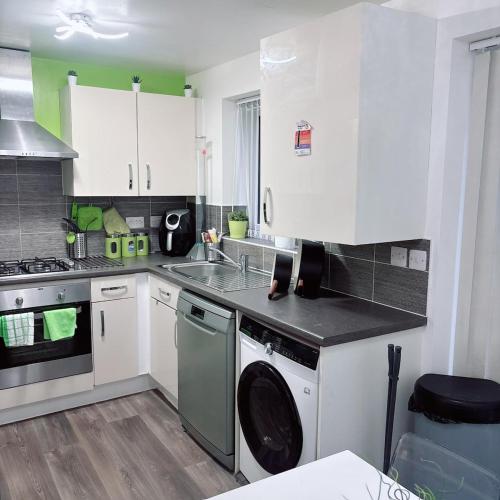 a kitchen with white cabinets and a washing machine at Ellas Stays in Farnworth