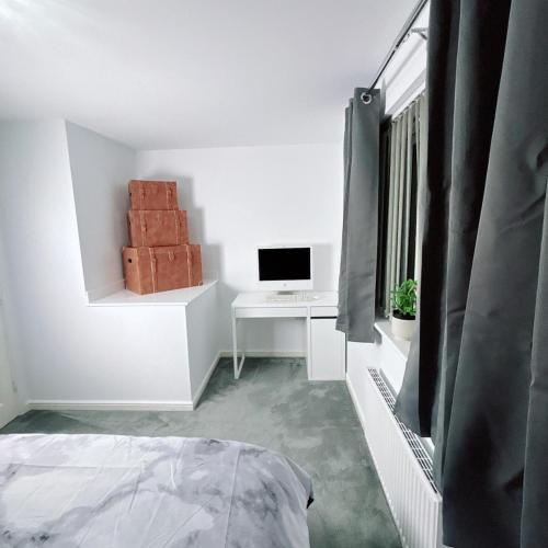 a bedroom with a bed and a desk with a computer at Ellas Stays in Farnworth