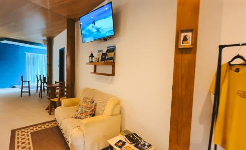 un salon avec un canapé et une télévision au mur dans l'établissement Sea Wolf Surf Hostel Campeche, à Florianópolis