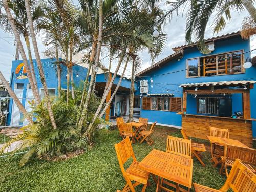 un groupe de tables et de chaises devant une maison dans l'établissement Sea Wolf Surf Hostel Campeche, à Florianópolis