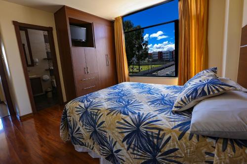 a bedroom with a bed and a large window at Hotel Portugal Confort in Ambato