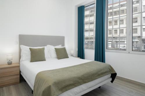 een slaapkamer met een groot bed en twee ramen bij Residência Lord Freitas I by An Island Apart in Funchal