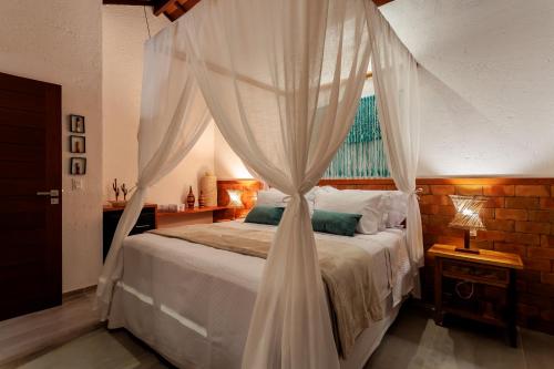 a bedroom with a canopy bed with a window at Tua Pousada Boutique Tatuamunha, Rota Ecológica dos Milagres, Porto de Pedras, Alagoas in Tatuamunha
