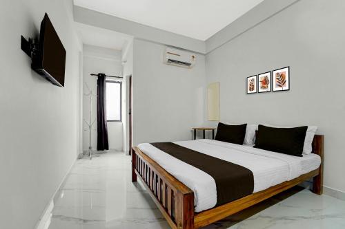 a bedroom with a bed and a television on a wall at Hotel O Moonlight Residency in Trivandrum