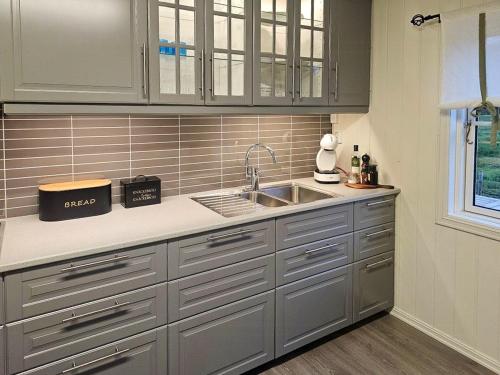 una cocina con armarios de acero inoxidable y fregadero en Charming Farm Stay On Averøy Island, en Lyngstad