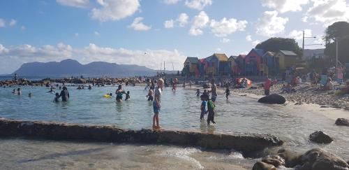 eine Gruppe von Menschen im Wasser an einem Strand in der Unterkunft Penn's Place in Muizenberg