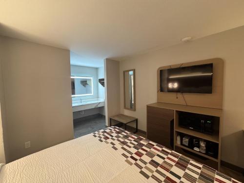 a bedroom with a bed and a flat screen tv at Red Roof Inn Arlington - Entertainment District in Arlington