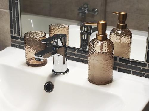a bathroom sink with two bottles and a mirror at Golden Home Törökbálint in Törökbálint