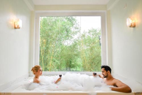 deux personnes dans une baignoire avec une fenêtre dans l'établissement Grand Ranketha Resort, à Kalutara