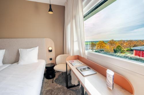 Una habitación de hotel con una cama, un escritorio y una ventana. en Hôtel AKENA Chalons-en-Champagne, en Châlons-en-Champagne