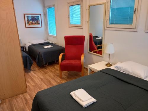 una camera con due letti e una sedia rossa di Hotel 24 - Apartments a Kemi