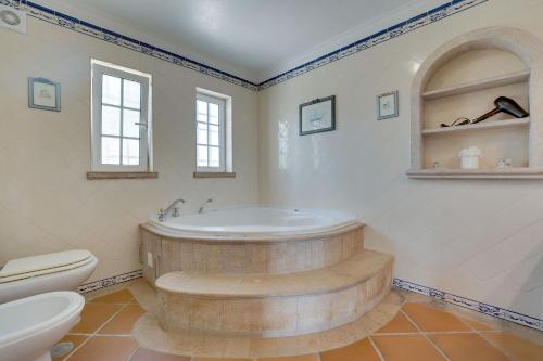een badkamer met een bad en een toilet bij Villa das Buganvilias by Delilah Collection in Albufeira