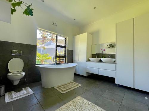 een badkamer met een bad, 2 wastafels en een toilet bij Kommetjie Mountain Oasis in Kommetjie