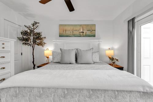 a white bedroom with a large bed with two lamps at La Barra #101 in St. Pete Beach