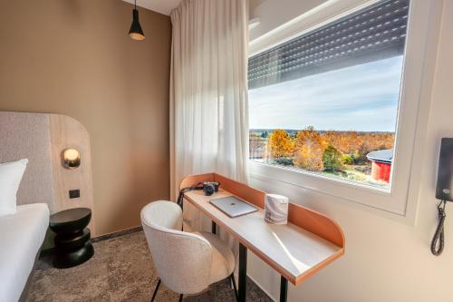 Una habitación de hotel con un escritorio y una ventana. en Hôtel AKENA Chalons-en-Champagne, en Châlons-en-Champagne
