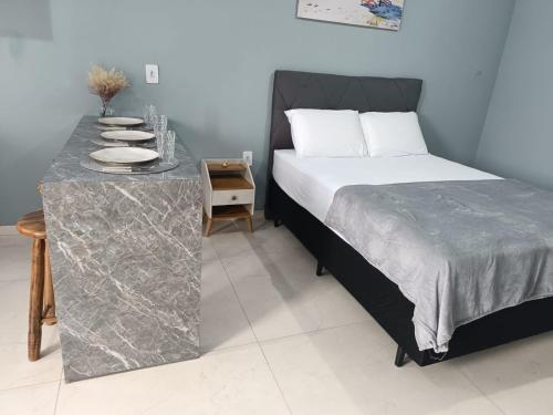 ein Schlafzimmer mit einem Bett und einem Tisch mit Tellern darauf in der Unterkunft Studios Próx. à Praia de São Miguel | 4,9 km Beto Carrero in Gravata