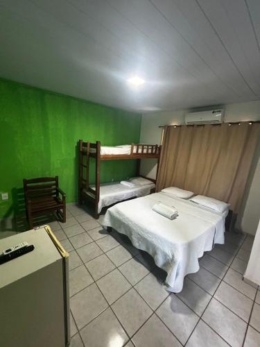 a bedroom with two beds and green walls at Pipa Hotel Pe na Areia in Pipa