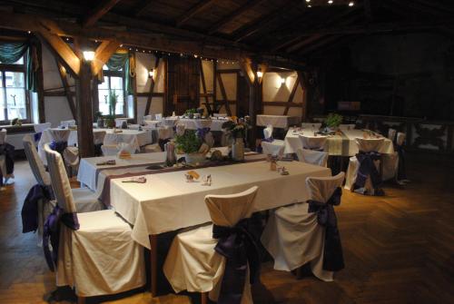 a room with tables and chairs with white tables and chairsearcher at Landhotel "Lichte Aue" Lichtenau in Stützengrün