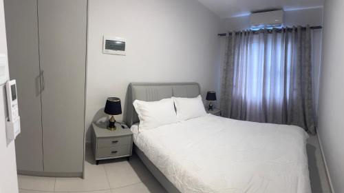 een slaapkamer met een wit bed en een raam bij The Nook in Gaborone