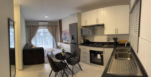 een keuken en woonkamer met een tafel en stoelen bij The Nook in Gaborone