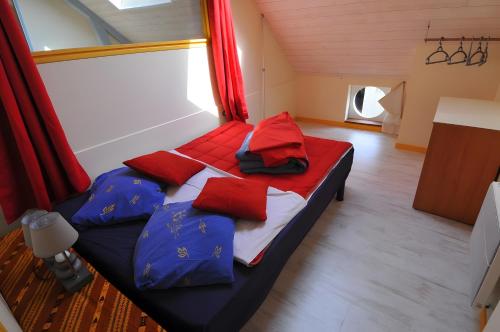 Bett in einem Zimmer mit roten und blauen Kissen in der Unterkunft Gîte Erziwezh in La Porte